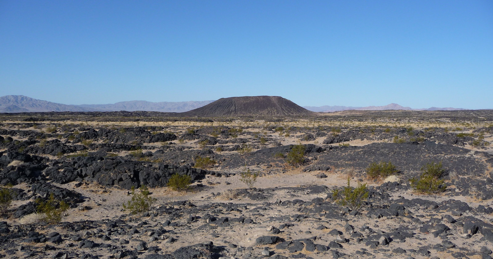 Amboy Crater and its dark volcanic field beside the Mojave Desert